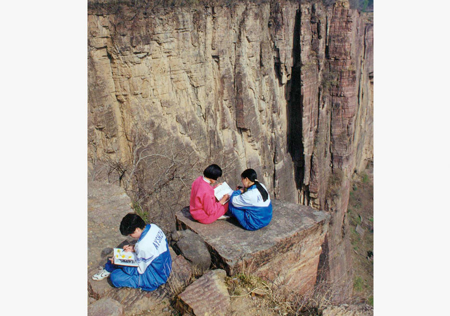 Estudiantes dibujan sentandos cerca de los acantilados en Guoliang, en la provincia de Henan, en esta foto de archivo.[Foto/VCG]
