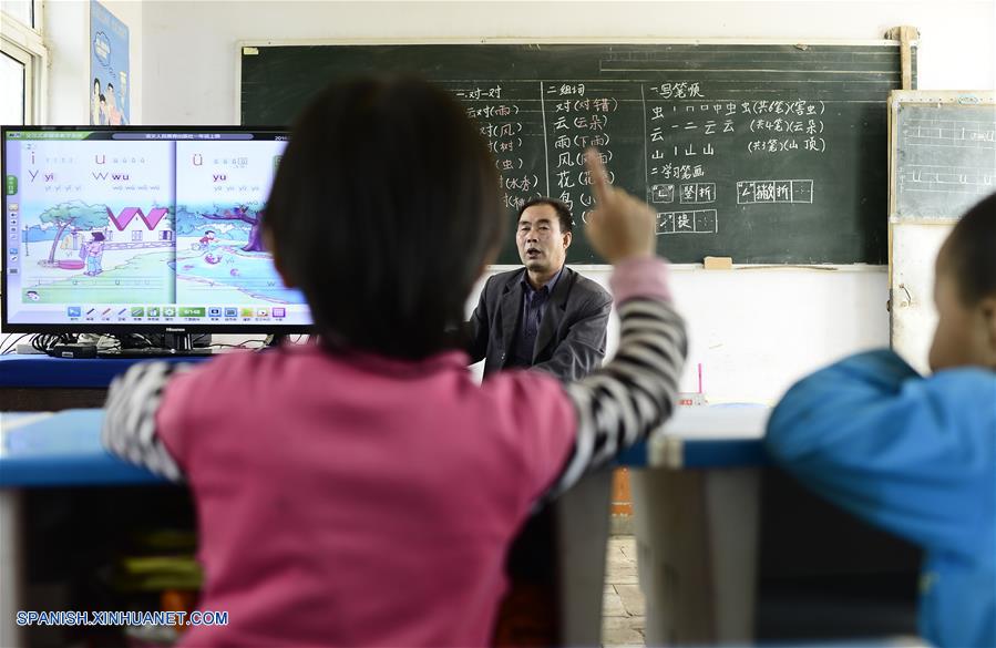 Imagen del 8 de septiembre de 2016 del maestro Hua Fulin (atrás), de 56 años de edad, el único profesor de la pequeña escuela de la villa de Kunlun, instruyendo a sus alumnos, en la villa de Kunlun de la ciudad de Haidong, provincia de Qinghai, en el noroeste de China. A unos 50 kilómetros de distancia del condado más cercano, la pequeña escuela de Kunlun ahora tiene sólo ocho alumnos y un maestro. (Xinhua/Zhang Hongxiang)