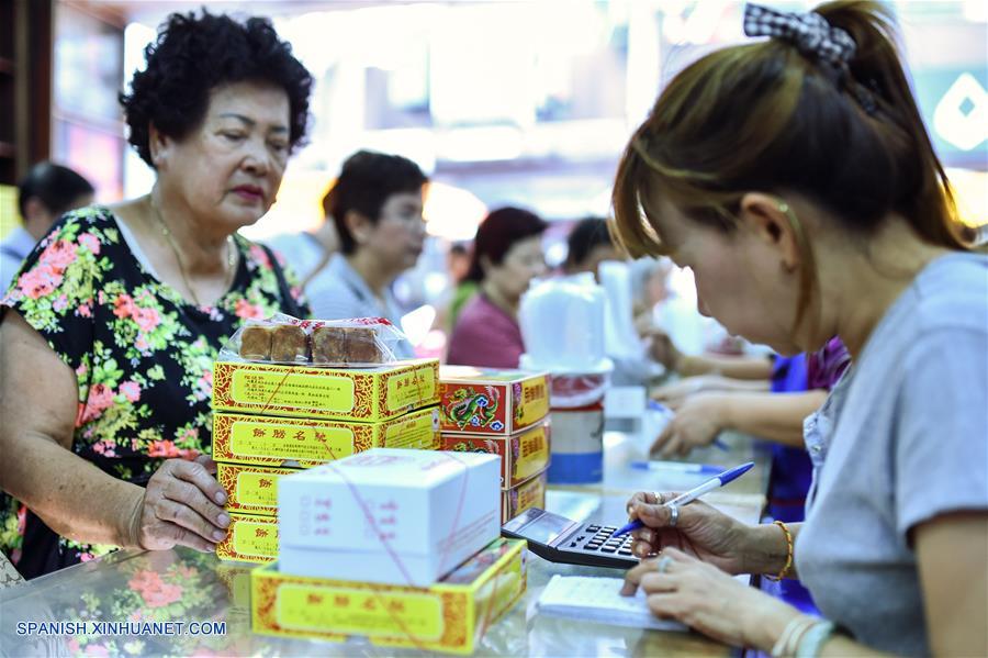 Una empleada (d) calcula el monto total de tartas de luna compradas por clientes previo al Festival de Medio Otoño en una pastelería en el barrio chino de Bangkok, Tailandia, el 14 de septiembre de 2016. En Tailandia, donde muchos ciudadanos son de origen chino, las personas a menudo adoran a la luna y otras deidades mientras comen tartas de luna junto a los miembros de su familia para celebrar el festival. El Festival de Medio Otoño cae el 15 de septiembre este año. (Xinhua/Li Mangmang)