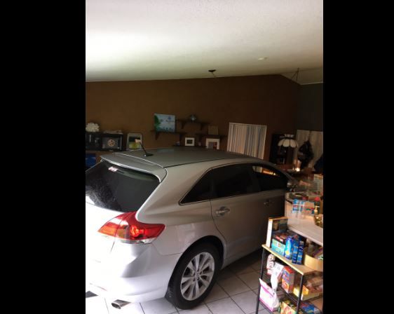 Una familia estaciona el auto en la sala de su casa para protegerlo del huracán Matthew