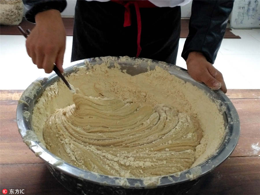 Un maestro de dulces tradicionales sofríe soja, uno de los tres ingredientes claves en el sabor del Zi Dou Tang. 