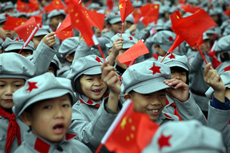 Jóvenes estudiantes chinas vestidas con el uniforme del ejército rojo ondean banderas nacionales durante la ceremonia de inauguración de una escuela primaria del ejército rojo en la fecha en que se conmemoró el 120 aniversario del natalicio de Mao Zedong. Luzhou, provincia de Sichuan. [Foto: IC]