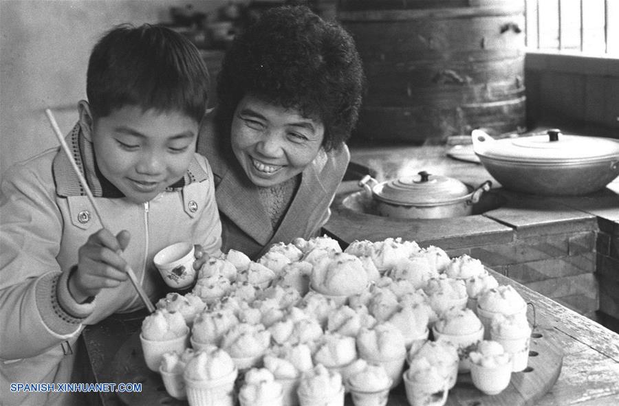  Imagen de archivo tomada en 1980, de Chen Suzhen (d) enseñando a su hijo a decorar panes al vapor, en la ciudad de Quanzhou de la provincia de Fujian, en el sureste de China. El espíritu más importante del Año Nuevo Lunar chino, o Festival de Primavera, es la reunión familiar. Es también la mejor época para que las personas de todas las edades se reúnan a disfrutar de una deliciosa comida. (Xinhua/Zheng Zhensun)