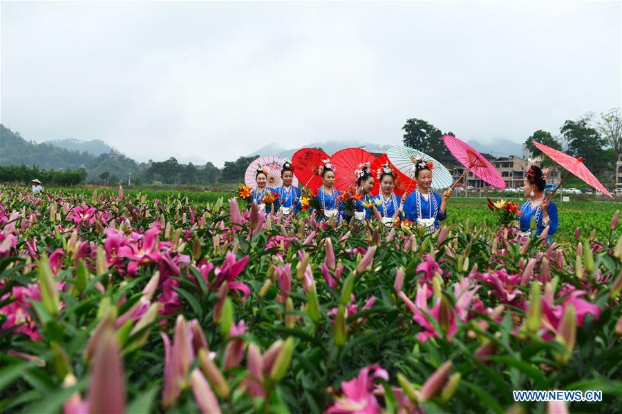Aldeanos visten el traje tradicional del grupo étnico Miao y posan junto a los turistas en el reino de los lirios de la aldea Wanghutun, en la provincia Guizhou, el 21 de mayo del 2017. (Foto: Yang Wenbin)