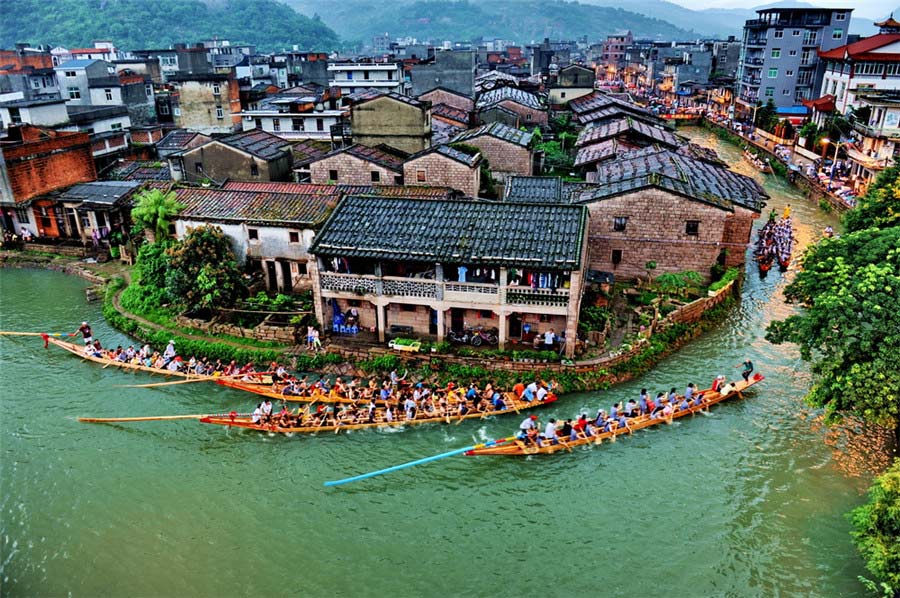 La gente se prepara para una carrera de botes de dragón en una ciudad con río. Foto de Deng Yijian. [Foto proporcionada por photoint.net]