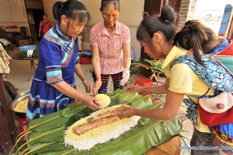 NANNING, mayo 29, 2017 (Xinhua) -- Imagen del 28 de mayo de 2017, de mujeres del grupo étnico Zhuang elaborando un "zhongzi" con forma de almohada en el municipio de Luobo en el distrito de Wuming de Nanning, en la Región Autónoma Zhuang de Guangxi, en el sur de China, el 29 de mayo de 2017. El "zongzhi"con forma de almohada en Luobo es elaborado con arroz glutinoso y carne. (Xinhua/Pan Huanqing)