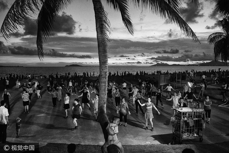Un grupo numeroso de personas baila bajo las palmeras en Sanya, provincia de Hainan, el 23 de julio de 2016. [Foto / VCG]