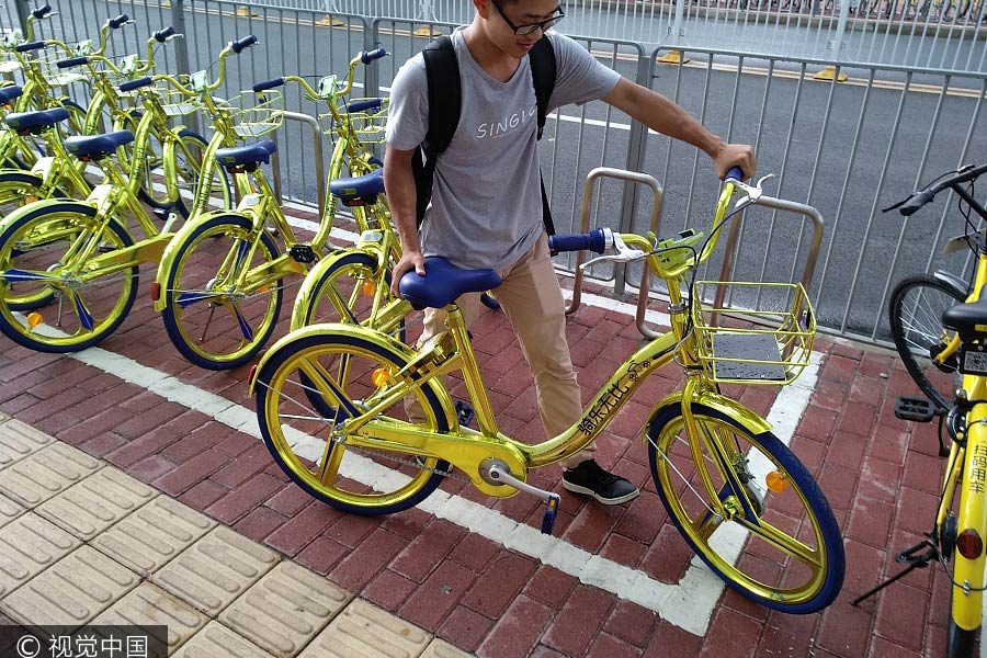 Un joven alquila una de las bicicletas compartidas doradas en Shenzhen, provincia de Guangdong, el 8 de junio de 2017. [Foto / VCG]