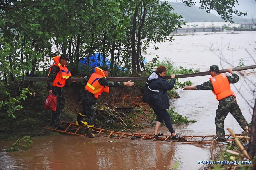 Bomberos rescatan a un poblador en la aldea Bajiapu, en el condado de Xiuyan de Anshan, en la provincia de Liaoning, en el noreste de China, el 4 de agosto de 2017. Una lluvia torrencial afectó al condado el jueves y viernes, dañando caminos, instalaciones de electricidad y cultivos en algunos municipios. Un total de 18,900 personas han sido trasladadas a lugares seguros, y la ciudad ha iniciado el nivel 1 de respuesta de emergencias para enfrentar las posibles inundaciones. (Xinhua/Yang Qing)