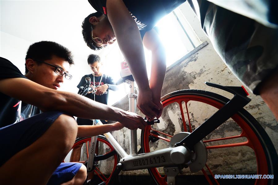 TIANJIN, agosto 21, 2017 (Xinhua) -- Despachadores de bicicletas compartidas desbloquean una bicicleta en un edificio residencial en Tianjin, en el norte de China, el 21 de agosto de 2017. A pesar del clima sofocante en Tianjin, los despachadores, que también son trabajadores de mantenimiento, viajan por la ciudad para asegurar que las biciclets estén en orden y funcionen bien. (Xinhua/Shi Songyu) 