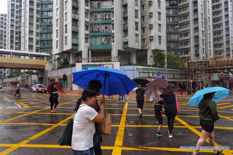 Personas caminan bajo la lluvia, en Hong Kong, en el sur de China, el 15 de octubre de 2017. El observatorio nacional de China prorrogó la alerta naranja por el tifón Khanun, que se está aproximando al país por la costa meridional trayendo fuertes vendavales y tormentas. (Xinhua/Wang Shen)