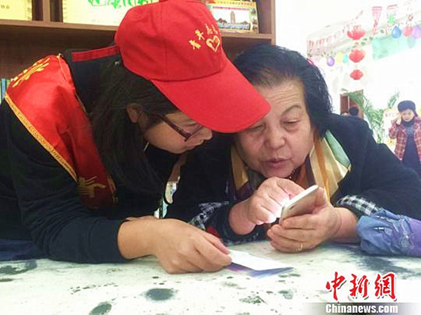 Un voluntario enseña a una persona de la tercera edad a usar wechat en Lanzhou, provincia de Gansu, 25 de octubre del 2017. [Foto: chinnews.com]