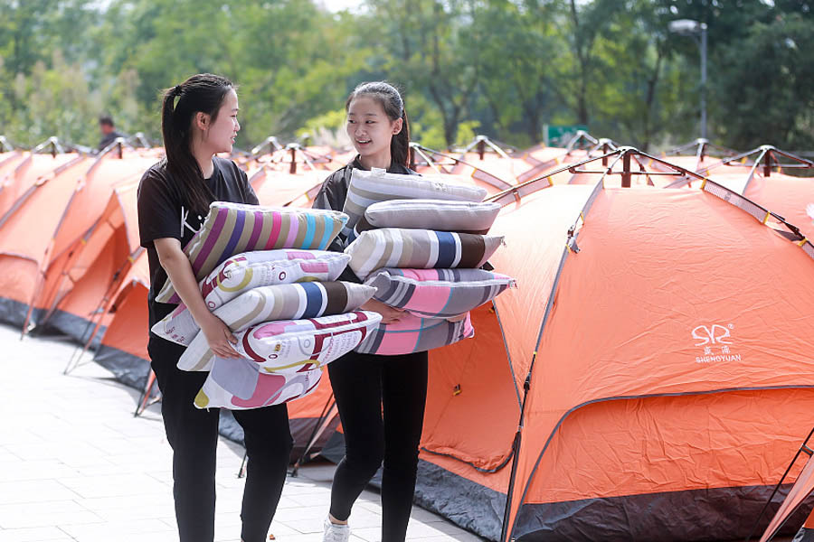 Dos miembros del personal de apoyo suministran almohadas para las camas del campamento laboral del Festival de Compras 11-11 o Día del Soltero en la sede de Alibaba en Hangzhou, provincia de Zhejiang.31 de octubre del 2017. [Foto: VCG]