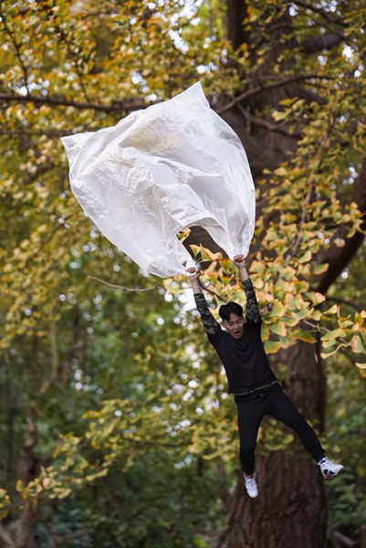 Una foto con el tema "Reduce la contaminación de las bolsas de plástico" muestra a un joven volando mientras sostiene una bolsa de plástico. (Foto proporcionada a chinadaily.com.cn)