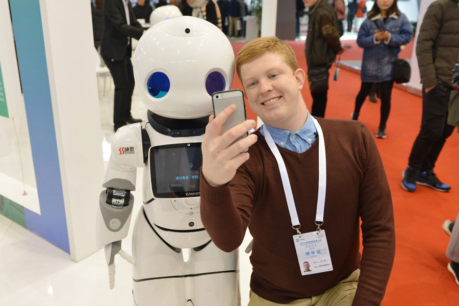 Un participante extranjero se hace una foto con un robot en la Cumbre Mundial de Fabricación Inteligente en Nanjing, provincia de Jiangsu, el 6 de diciembre de 2017. [Foto / IC]