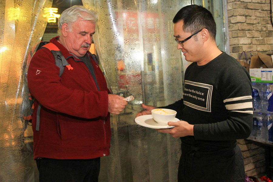 Un cliente paga a Si Shaojie después de cenar en la fonda Desi, Zhengzhou, provincia de Henan, 9 de noviembre del 2017.
