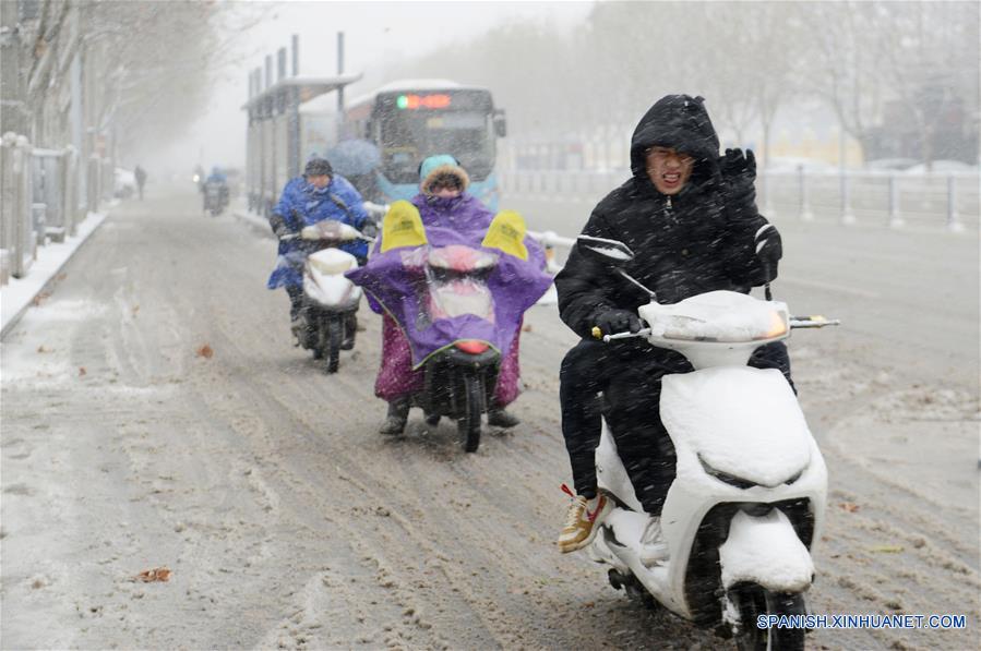 Personas transitan en medio de una nevada, en la ciudad de Fuyang, provincia de Anhui, en el este de China, el 3 de enero de 2018. Una ola de frío trajo la primera nevada de 2018 a varios lugares de China. (Xinhua/Dai Wenxue)