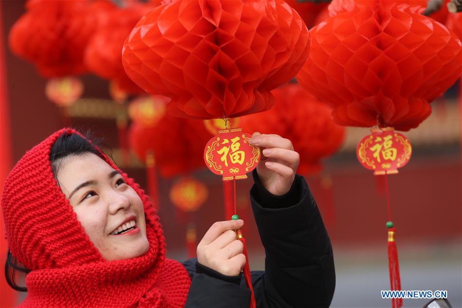 Una joven admira los faroles rojos que embellecen la puerta sur del parque Ditan, conocido también como el parque del Templo de la Tierra, Beijing, 27 de enero del 2018. [Foto: Xinhua]