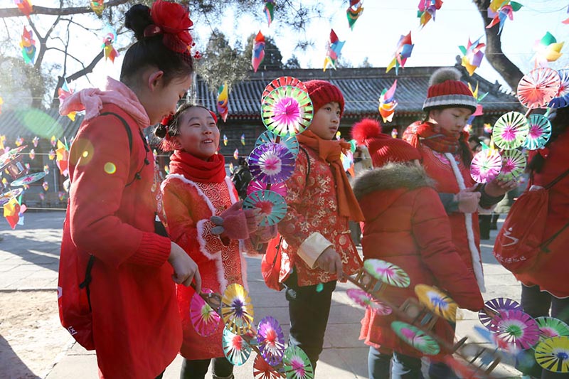 Los niños con trajes festivos de colores juegan con molinetes de colores en el Observatorio Antiguo en Beijing para celebrar el periodo del calendario lunar Comienzo de la Primavera, que comenzó el domingo. [Foto de Wang Zhuangfei / chinadaily.com.cn]