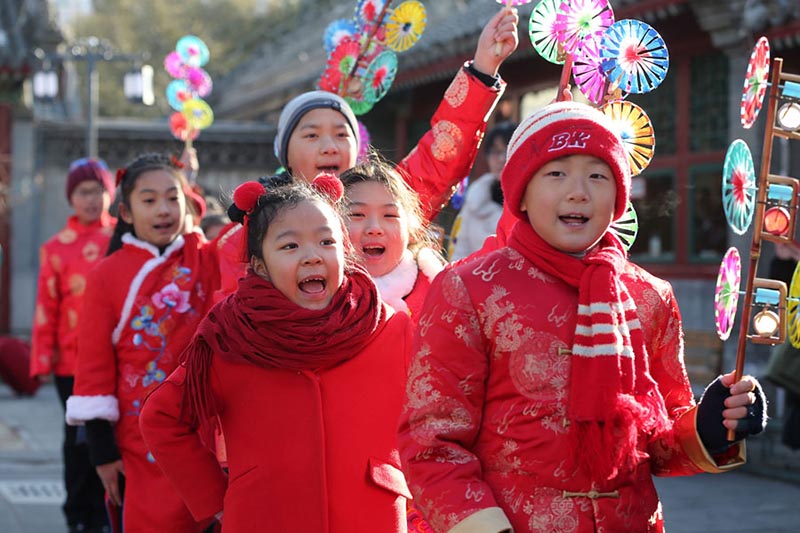 Los niños con trajes festivos de colores juegan con molinetes de colores en el Observatorio Antiguo en Beijing para celebrar el periodo del calendario lunar Comienzo de la Primavera, que comenzó el domingo. [Foto de Wang Zhuangfei / chinadaily.com.cn]