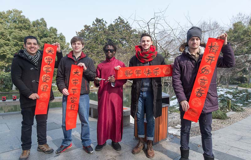Los estudiantes extranjeros muestran sus coplas con caligrafía china en el Lago Oeste de Hangzhou, capital de la provincia de Zhejiang, el 2 de febrero de 2018. [Foto / IC]