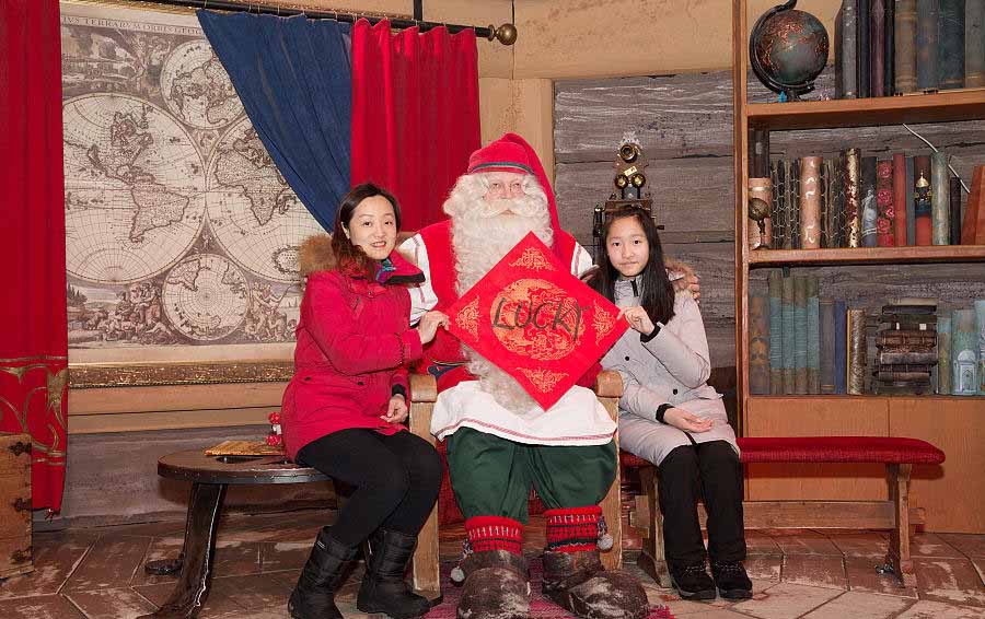 Santa Claus posa para una foto con turistas chinos en Rovaniemi, Finlandia, el 7 de febrero del 2018. [Foto: VCG]