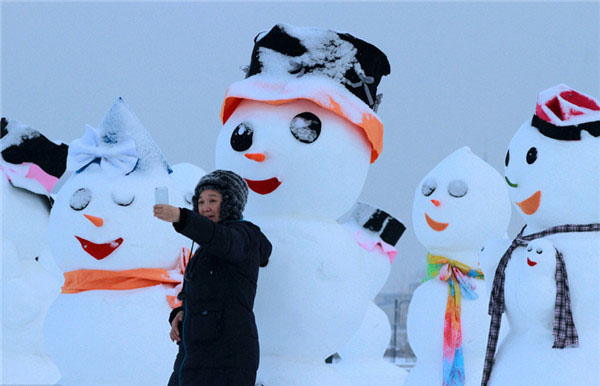 Un visitante posa junto a un gracioso muñeco de nieve que se exhibe en el Parque del Hielo y la Nieve de Harbin, provincia de Heilongjiang, que atrae a muchos visitantes de diferentes latitudes de China. [Foto: IC]