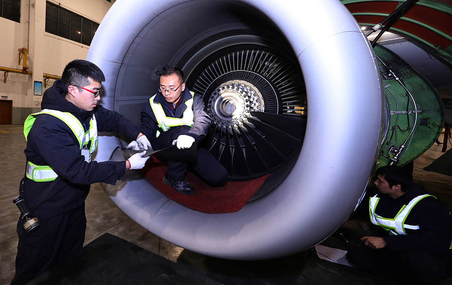 Dos ingenieros comprueban el motor de un avión en un centro de mantenimiento en la ciudad de Wuhan que trabaja para la aerolínea China Southern, provincia de Hubei, 9 de febrero del 2018. [Foto: VCG]