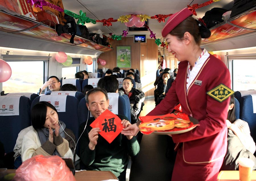El 15 de febrero de 2018, en el tren G387 que va desde la estación Beijing Sur a Dalian Norte, la azafata jefa Tian Sijie (derecha) regala el carácter “fu” de la buena suerte a los pasajeros que viajaban en este tren. Fuente de la imagen: Gao Jinxu / Pueblo en Línea