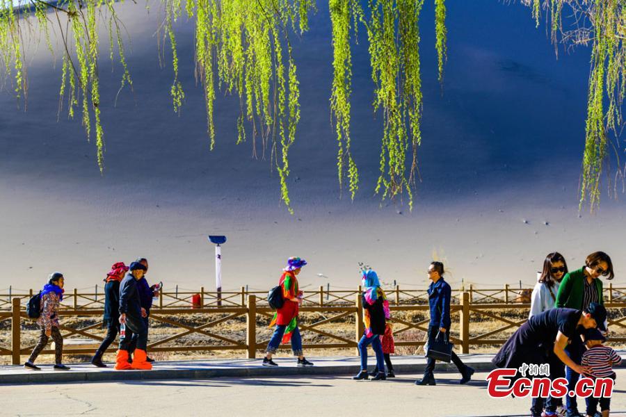Los turistas visitan las montañas arenosas cantantes de Dunhuang 