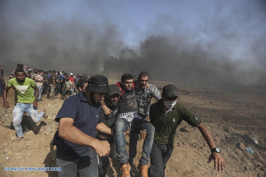 GAZA, junio 8, 2018 (Xinhua) -- Manifestantes palestinos cargan a un hombre herido durante enfrentamientos con soldados israelíes, en la frontera entre Gaza e Israel, en el este de la Ciudad de Gaza, el 8 de junio de 2018. Al menos cuatro manifestantes palestinos murieron y 618 resultaron heridos por soldados israelíes durante los enfrentamientos ocurridos el viernes cerca de la frontera Israel-Gaza, dijeron fuentes palestinas. (Xinhua/Wissam Nassar)