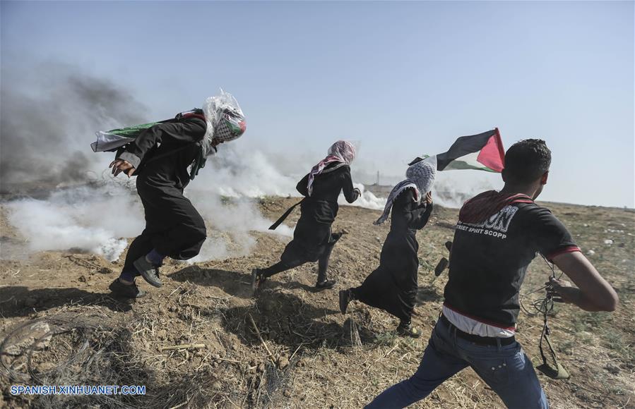 GAZA, junio 8, 2018 (Xinhua) -- Manifestantes palestinos corren para cubrirse del gas lacrimógeno lanzado por soldados israelíes durante enfrentamientos en la frontera entre Gaza e Israel, en el este de la Ciudad de Gaza, el 8 de junio de 2018. Al menos cuatro manifestantes palestinos murieron y 618 resultaron heridos por soldados israelíes durante los enfrentamientos ocurridos el viernes cerca de la frontera Israel-Gaza, dijeron fuentes palestinas. (Xinhua/Wissam Nassar)