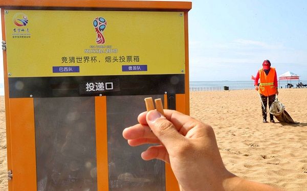 En la playa, una persona deposita una colilla de cigarro en un cenicero público rotulado con los nombres de dos equipos de la Copa Mundial de Fútbol Rusia 2018, Qinhuangdao, provincia de Hebei, China. [Foto: VCG]