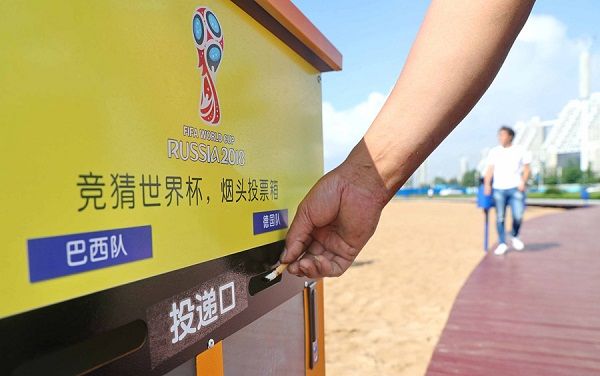 En la playa, una persona deposita una colilla de cigarro en un cenicero público rotulado con los nombres de dos equipos de la Copa Mundial de Fútbol Rusia 2018, Qinhuangdao, provincia de Hebei, China. [Foto: VCG]