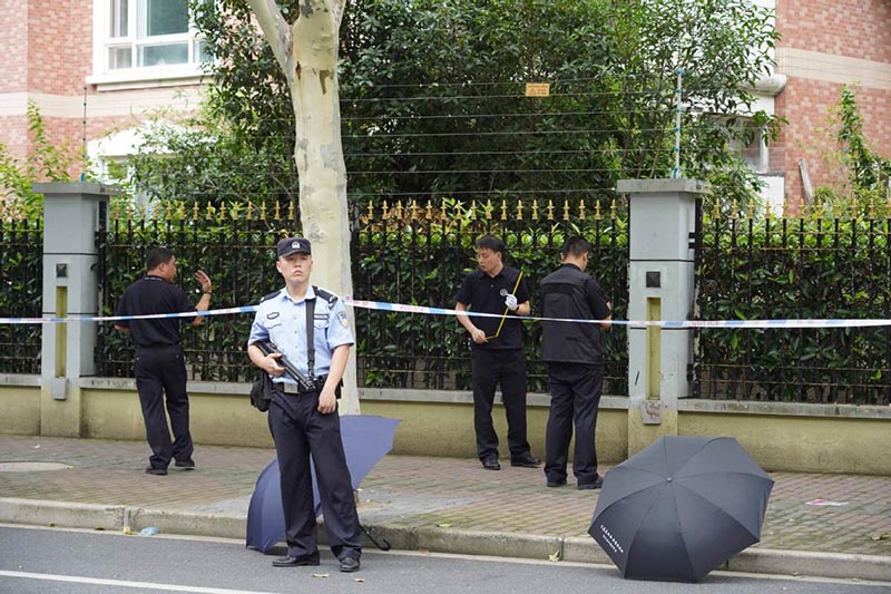 La policía cubre con paraguas la sangre en la escena del ataque con cuchillo ocurrido en Shanghai. [Foto: Gao Erqiang]. 