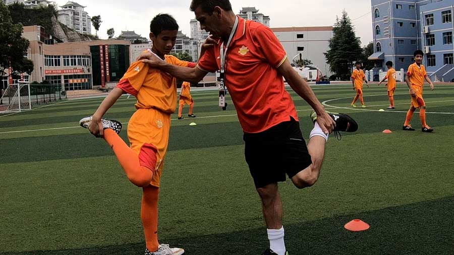 El entrenador español José (derecha) y el chileno Piri estrenan a niños chinos en la escuela Zhenghua en la ciudad de Kaili, suroeste de China.