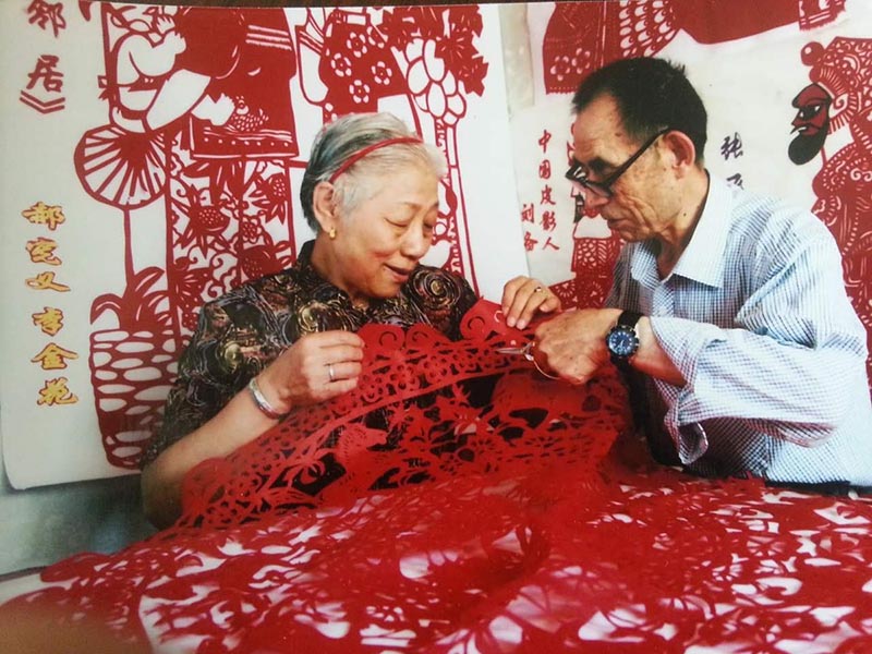 Hao Xianyi demuestra las habilidades de corte de papel a un entusiasta. [Foto por Xiao Ying / Por China Daily]