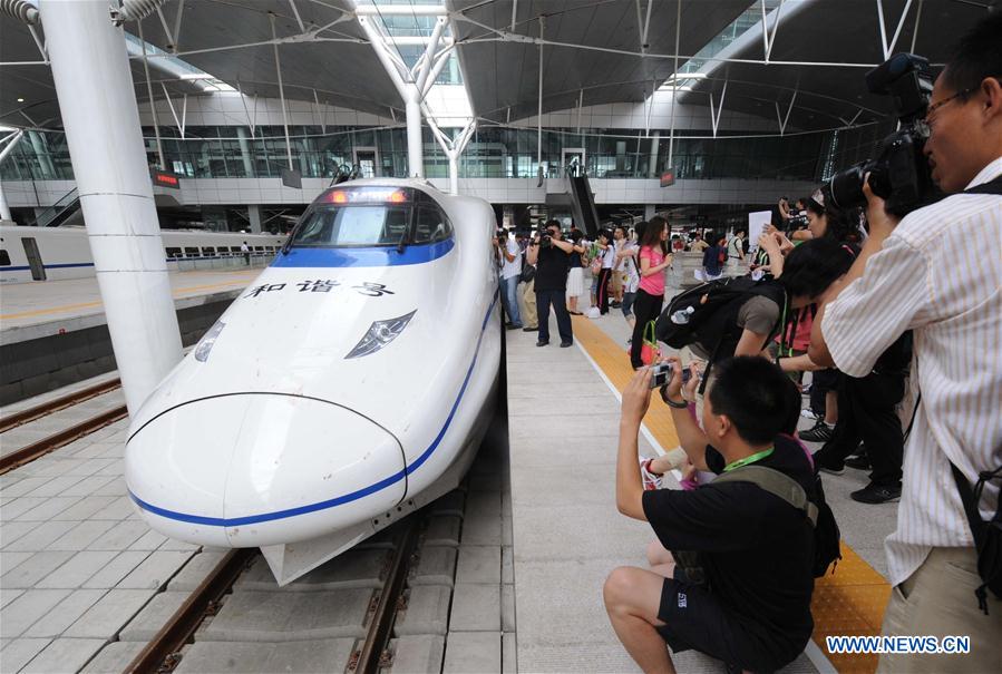 La gente toma fotos de un tren bala interurbano de alta velocidad Beijing-Tianjin en la estación de tren de Tianjin, norte de China, el 31 de julio de 2008. (Xinhua / Li Wen)