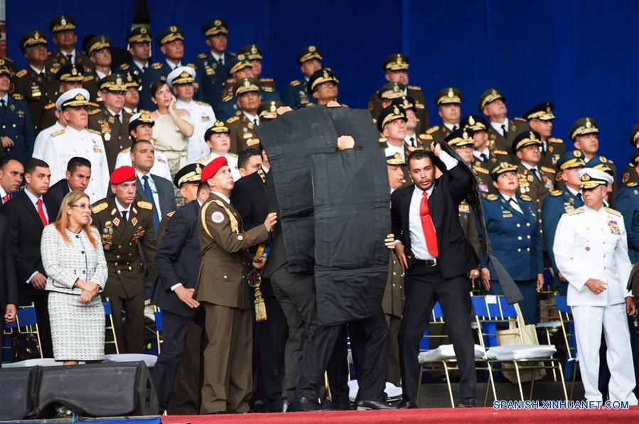 Elementos de seguridad protegen al presidente de Venezuela, Nicolás Maduro, luego que su discurso fuera interrumpido, durante un acto para conmemorar el 81 aniversario de la Guardia Nacional Bolivariana de Venezuela, en la Plaza Bolívar, en Caracas, Venezuela, el 4 de agosto de 2018. Durante una ceremonia conmemorativa del 81 aniversario de la Guardia Nacional Bolivariana de Venezuela en la que ofrecía un discurso el presidente venezolano, Nicolás Maduro, ocurrió el sábado un suceso inesperado que conllevó a la suspensión abrupta de la transmisión y del acto presidencial. Confirman atentado contra presidente Maduro durante acto militar en Caracas. (Xinhua/Str)