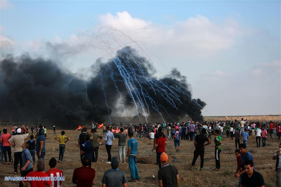 GAZA, agosto 3, 2018 (Xinhua) -- Manifestantes palestinos se reúnen mientras una lluvia de latas de gas lacrimógeno disparadas por soldados israelíes caen al suelo durante enfrentamientros en la frontera entre Gaza e Israel, en el este de la Ciudad de Gaza, el 3 de agosto de 2018. De acuerdo con información de la prensa local, un palestino fue asesinado y otros 220 fueron heridos por soldados israelíes el viernes durante enfrentamientos cerca de la frontera entre Gaza e Israel, informó el vocero del ministro palestino de Salud en la Franja de Gaza. (Xinhua/Str)