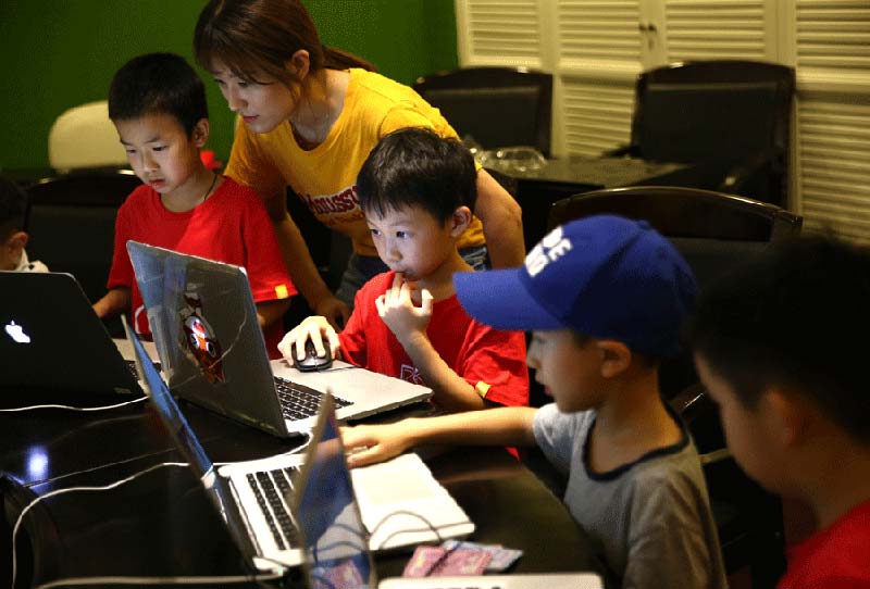 Un profesor explica cómo utilizar la codificación para crear juegos en un campamento de verano organizado por Codemao en Beijing. [Foto: Zou Hong/ China Daily]