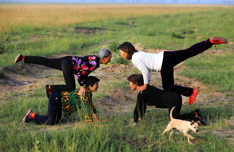 Temprano en la mañana, cuatro aldeanas practican yoga en el campo. [Foto: Zhu Xingxin/China Daily]