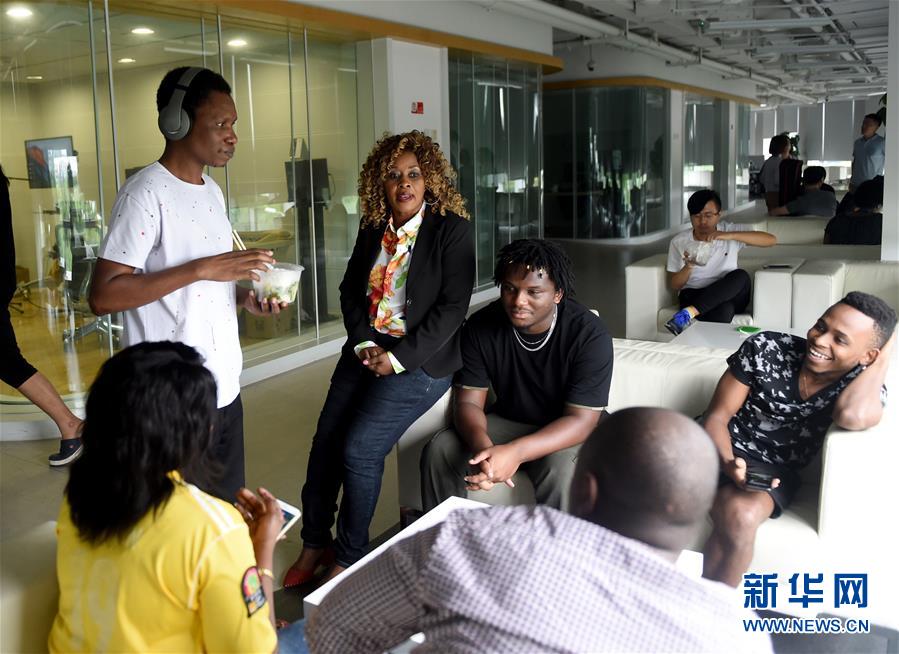 Al tiempo de descanso, Hilde(la tercera a la izquierda) charla con sus colegas tanzaniano en la sede de StarTimes Group. Yizhuang, Beijing, el 14 de agosto de 2018. (Foto: Luo Xiaoguang / Xinhua)