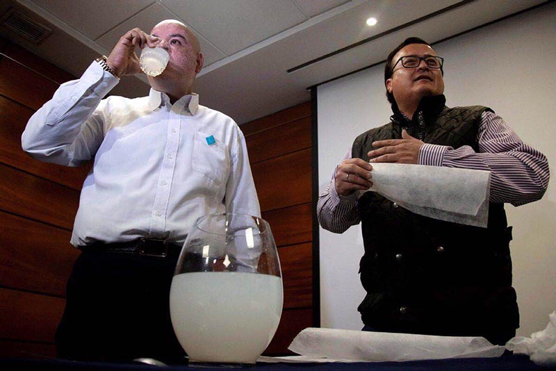 El empresario chileno Roberto Astete (a la izquierda) bebe la solución de PVA disuelto en agua para demostrar que los restos de las bolsas solubles no son peligrosos. (Foto: Claudio Reyes)