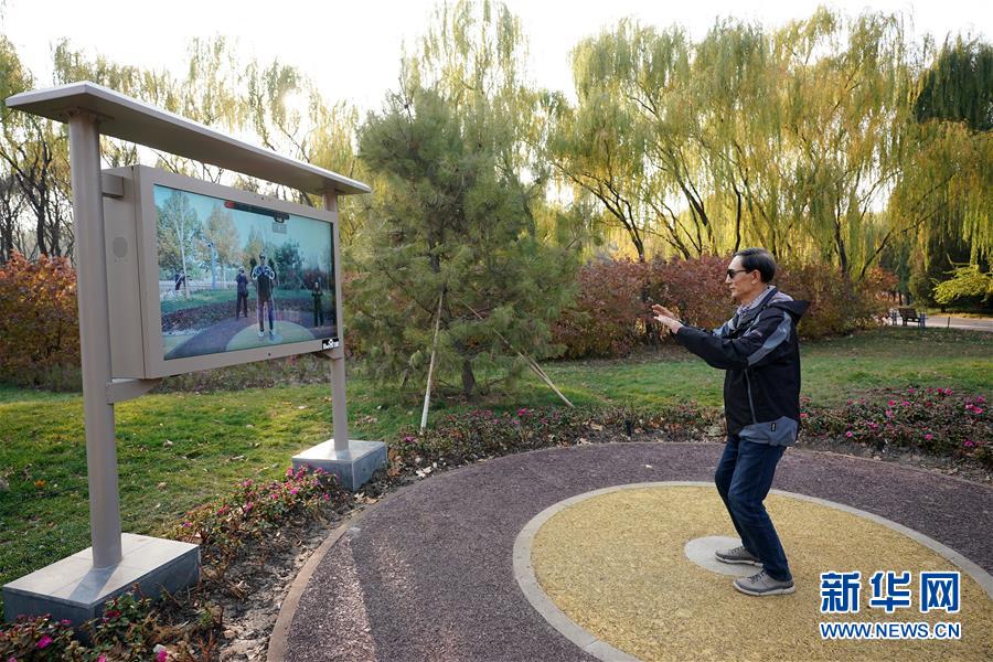 El 1 de noviembre, en el parque Haidian, un ciudadano sigue al instructor en la pantalla del dispositivo inteligente para aprender taichí. La cámara en la parte superior de la pantalla puede capturar todo el movimiento corporal del usuario en tiempo real y anotar la acción. 