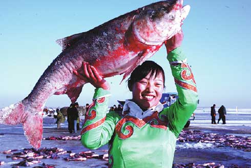 Una mujer muestra un gran pez capturado durante la temporada de pesca en el lago Chagan. [Foto: proporcionada]