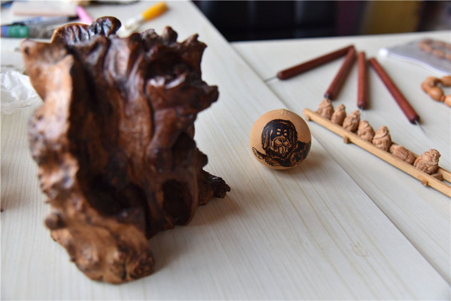 Obras de arte hechas en semillas de aceitunas, talladas por Zhu. [Foto: Qian Lei/ Chinadaily.com.cn]