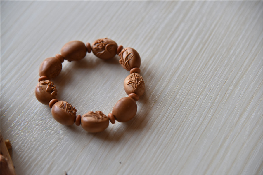 Un brazalete hecho de semillas de aceitunas, tallado por Zhu. [Foto: Qian Lei/ Chinadaily.com.cn]