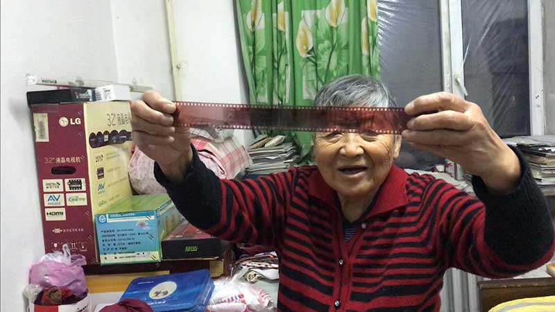 Zhang Ying, de 93 años, sostiene un rollo de película que guarda en su archivo. [Foto: Wang Kun/ Chinadaily.com.cn]