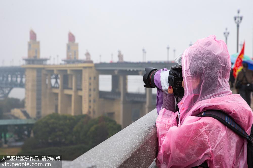 La gente en Nanjing desafía a la lluvia cruzando el recién renovado puente sobre el río Yangtse